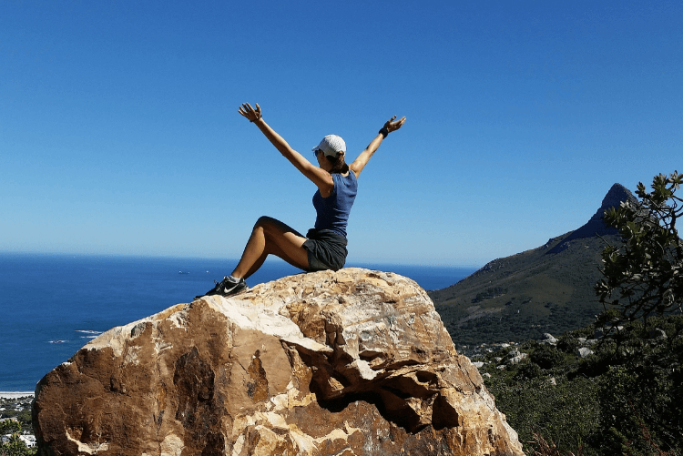 Happy Woman Sitting On Rock By The Sea